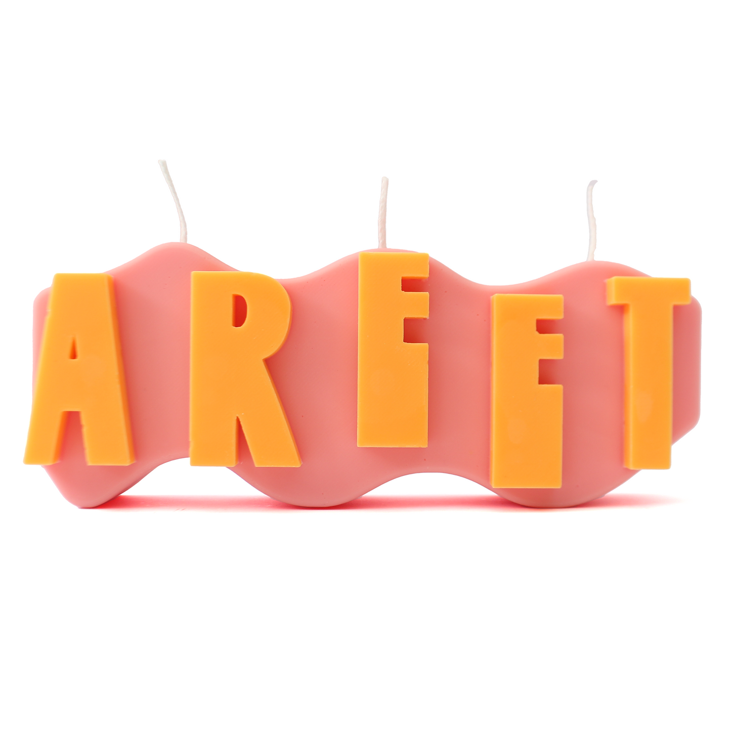 A decorative candle with a wavey body and protruding text. Measuring 17cm long and 7cm high. The body of the candle is coral pink with orange raised letters spelling AREET from left to right. It has three wicks spread across the top of the body evenly.