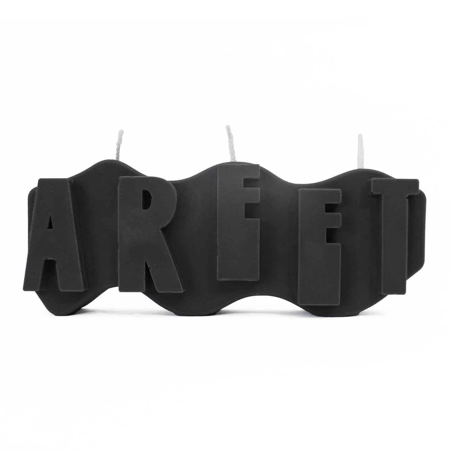 A decorative candle with a wavey body and protruding text. Measuring 17cm long and 7cm high. The candle is charcoal black with raised letters spelling AREET from left to right. It has three wicks spread across the top of the body evenly.