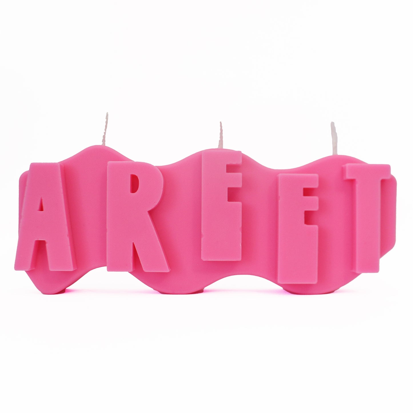 A decorative candle with a wavey body and protruding text. Measuring 17cm long and 7cm high. The candle is neon pink with raised letters spelling AREET from left to right. It has three wicks spread across the top of the body evenly.