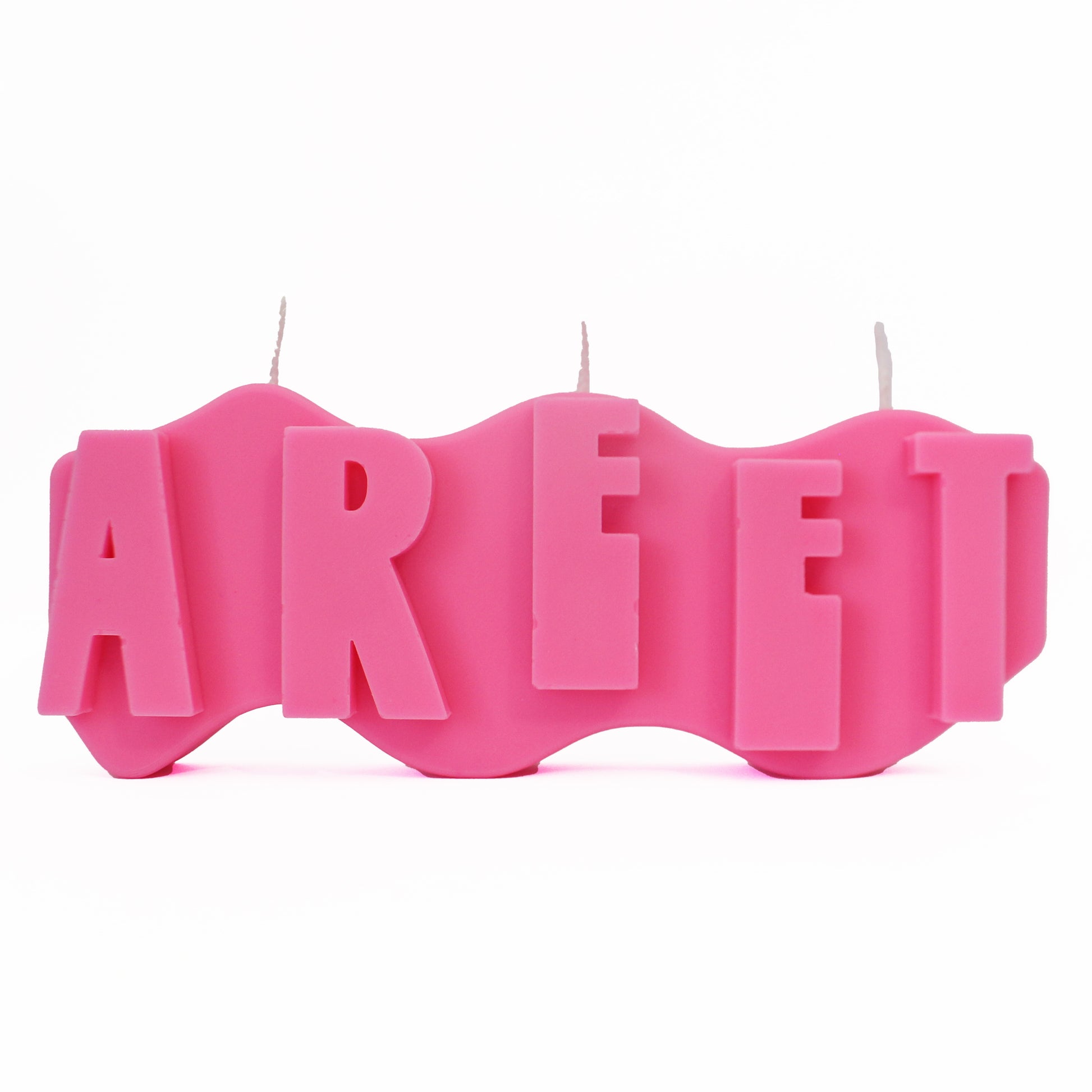 A decorative candle with a wavey body and protruding text. Measuring 17cm long and 7cm high. The candle is neon pink with raised letters spelling AREET from left to right. It has three wicks spread across the top of the body evenly. 